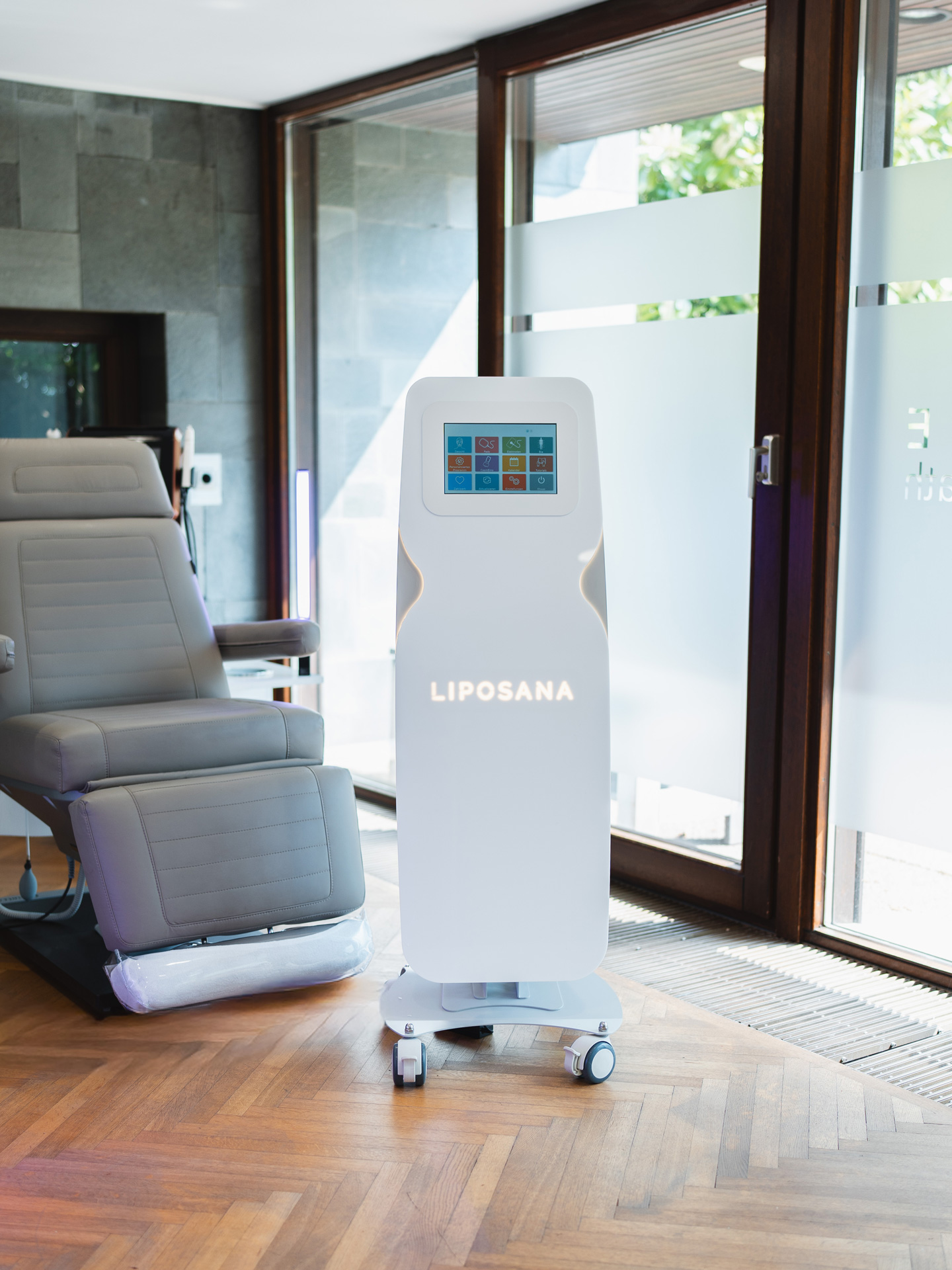 Liposana3 NEO device with touchscreen next to a grey treatment couch