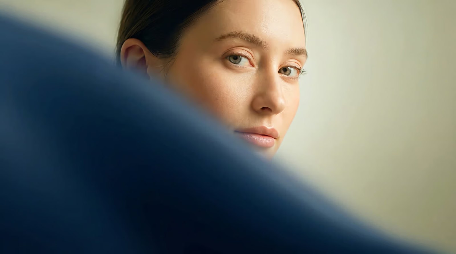 Young woman looking at the camera from behind a blurred dark blue foreground