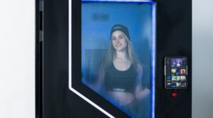 Frau in der blau beleuchteten POWERCAB-STORM-Kältekammer, schwarze Tür mit Sichtfenster und Tablet